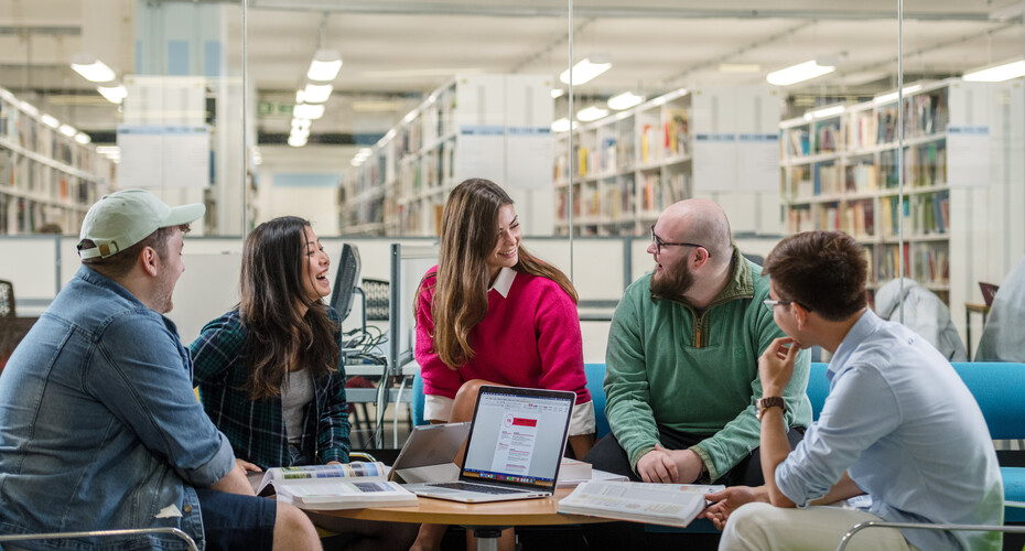 Students of different ages talking together around a table by the library