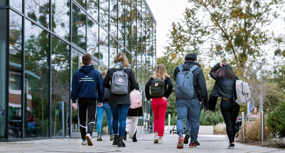 Students walk past a large glass fronted building