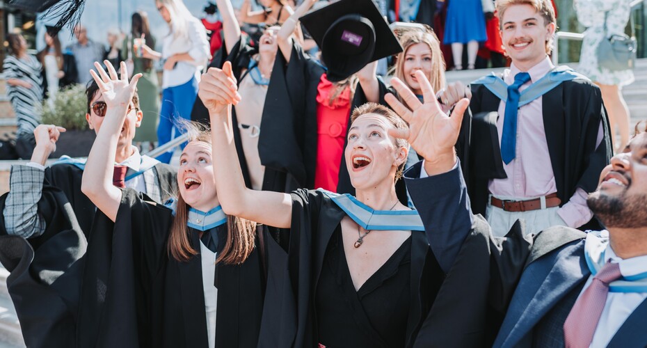 group of students throwing graduation mortar boards into the air