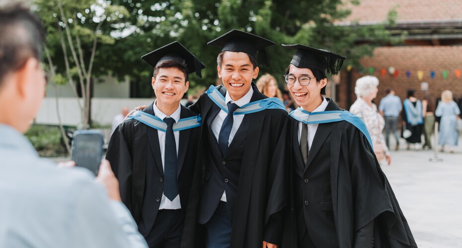 Three students have their photo taken outside at graduation