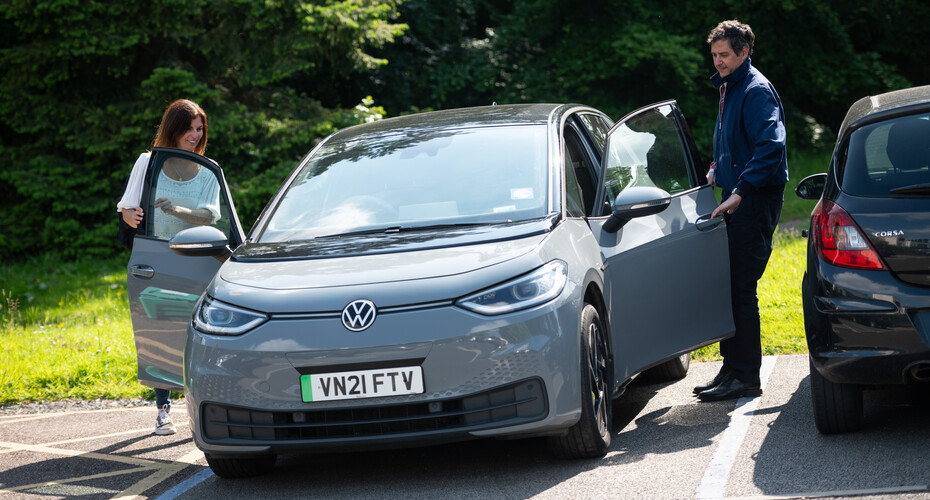A male and female opening doors of a grey VW car