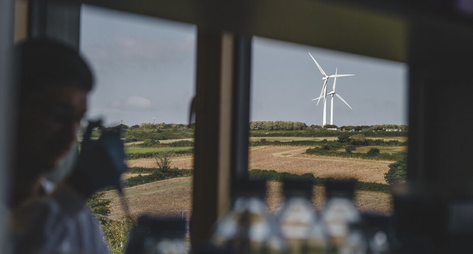 A researcher working in a lab with windows looking out on wind turbines