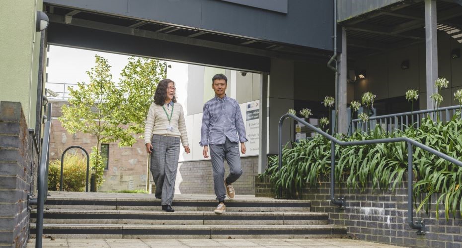 Two people walking on Penryn Campus