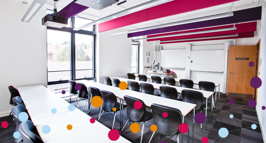 Empty modern classroom with rows of black chairs and white tables, a projector, and large windows. Colourful dots are overlaid in the foreground.