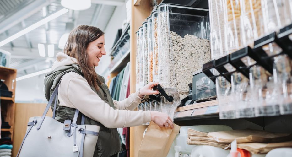 sustainable zero packing shop. Female student filling brown paper bag with cereal.
