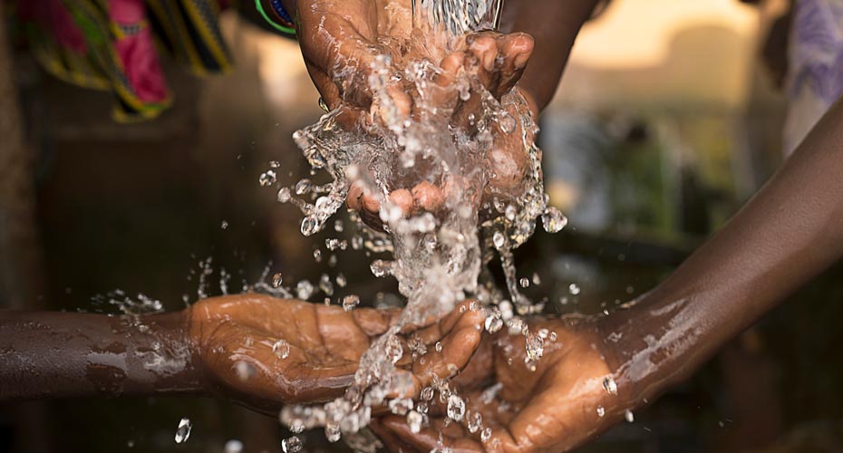 two pairs of hands washing in water from tap