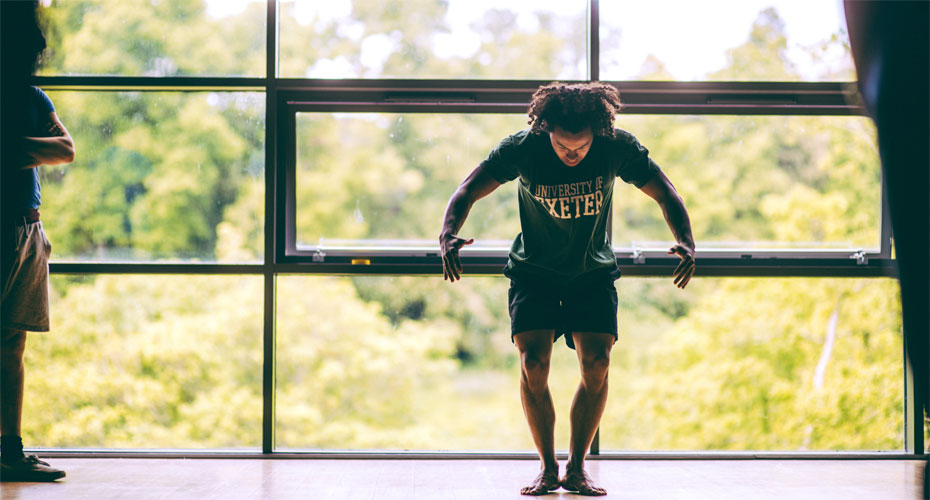 Drama student in the drama studio, wearing an Exeter University green top with logo