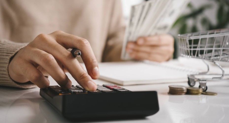 Woman counting and calculate cost money with calculator at home. Budget of disadvantaged and low income family for rising food and grocery store prices and expensive daily consumer goods concept. - stock photo