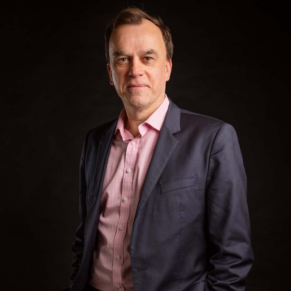 Man in black suit stood against a black background