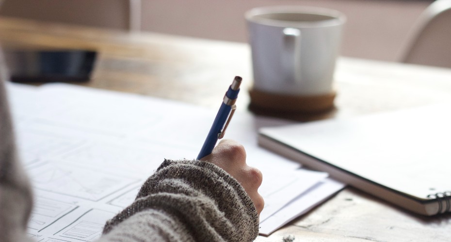 A student holding a mechanical pencil, writing on paper.