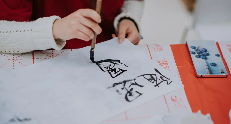 A student writing Chinese characters in paint.