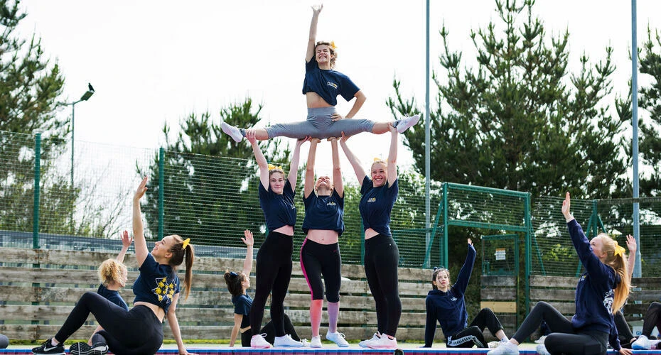 The cheerleading society lifting one of their members into the air