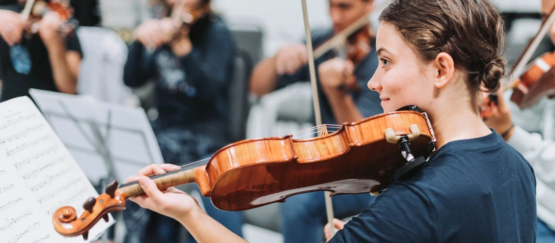 A student playing the violin as part of a student orchestra