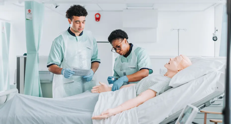 Two nurses practicing treatment on a prosthetic patient