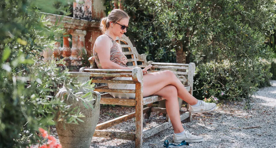 A student relaxing on a bench in the Italian Garden on Penryn Campus