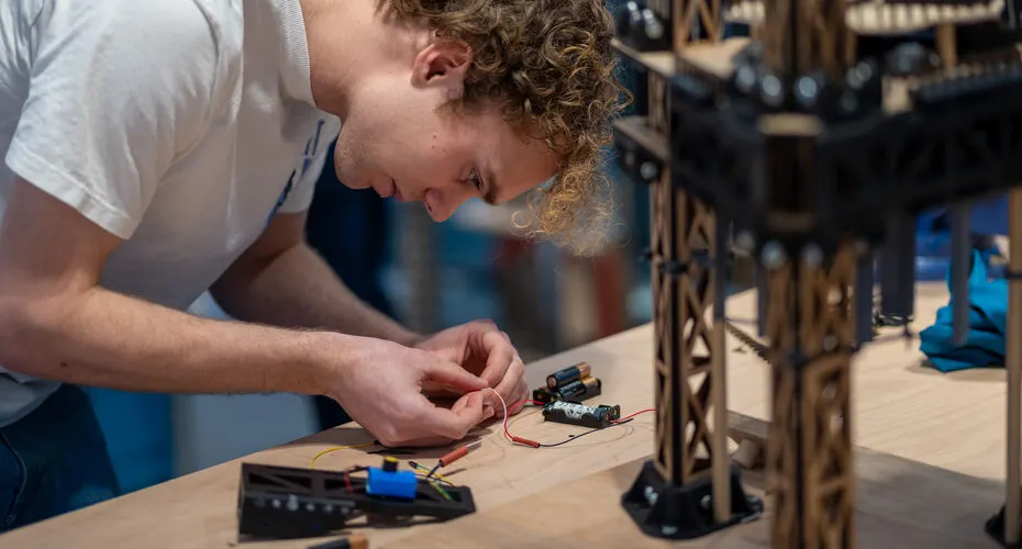 Engineering student concentrating on creating a model structure in a lab.