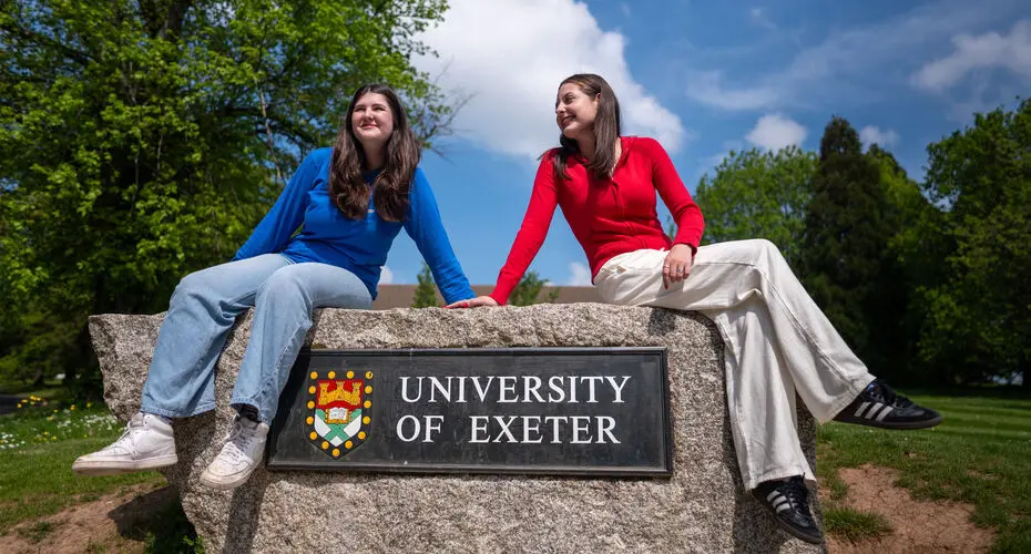 Two students sitting on the University of Exeter rock