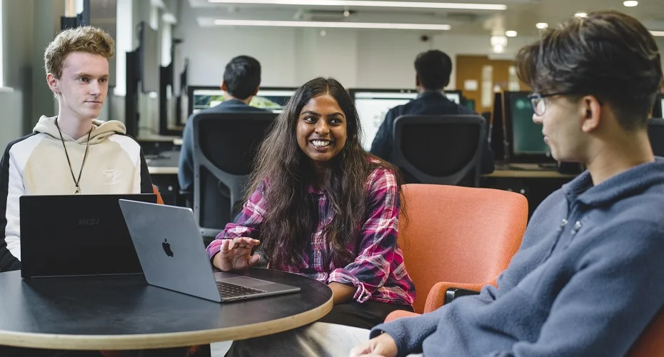 A group of Computer Science students having a discussion sat around laptops.
