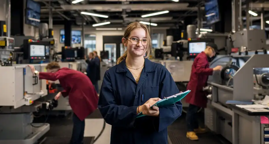 A PGR student stood in a learning space holding a clipboard