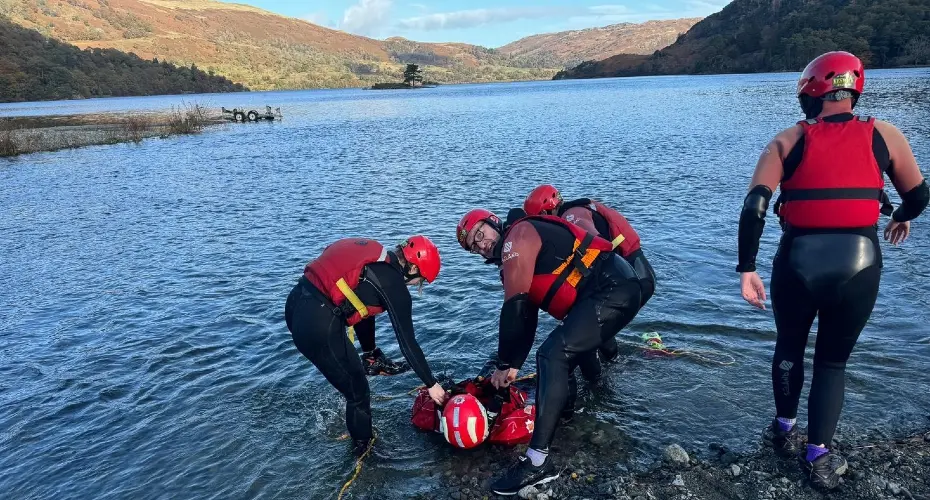 Extreme Medicine students on a search and rescue residential. Several students are pulling a demo patient out of the water, mountains in the background.