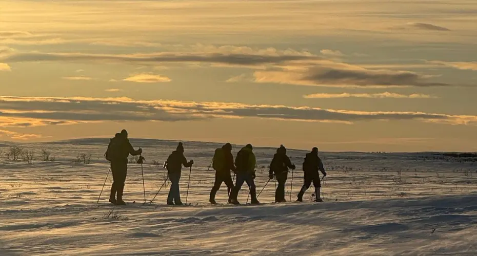 Group of MSc Extreme Medicine students walking across a snowy environment on skis with back packs