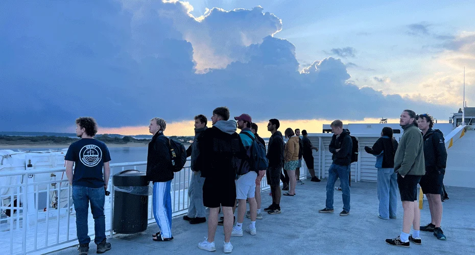 A group of renewable energy students looking out over an estuary at sunset