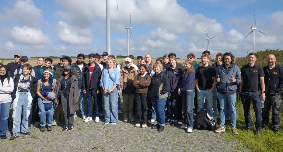 A group of students standing in front of wind turbines