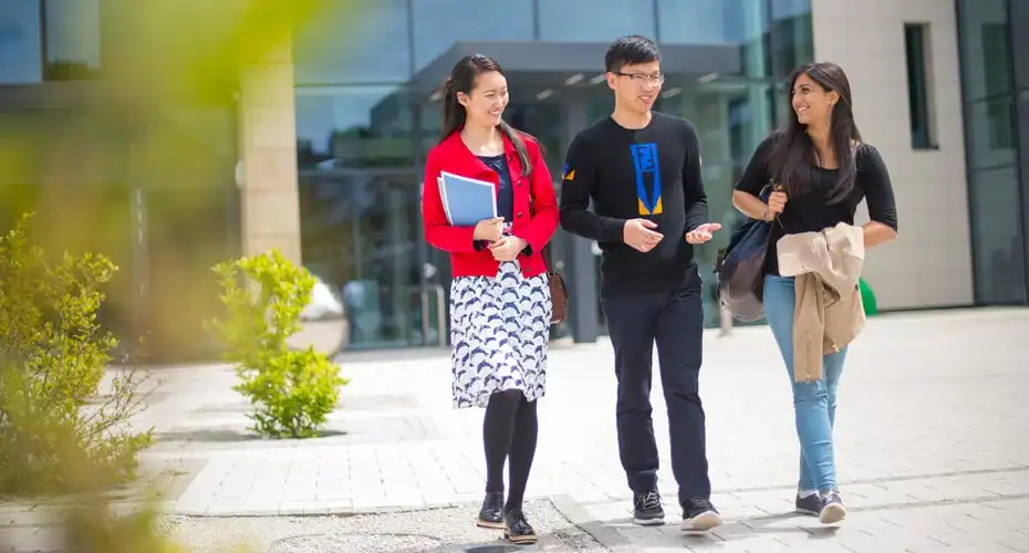 Three students walking and chatting together on campus